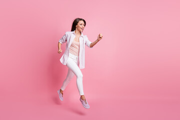 Fototapeta na wymiar Full length photo of purposeful young lady wear casual white outfit jumping running hands arms fists isolated pastel pink color background