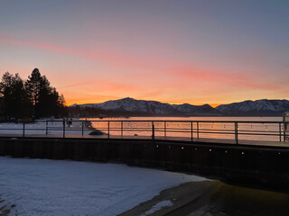 Pink and orange skies at sunset over Lake Tahoe, as seen from a snowy beach