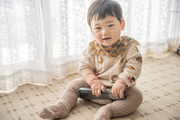 リビングでリモコンで遊ぶ赤ちゃん