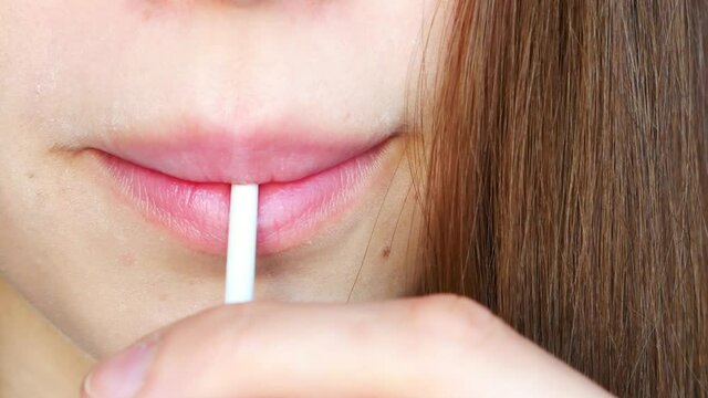 Close-up of a girl's lips sucking a green lollipop