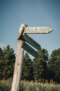Vertical shot of an old wooden pointer showing the roads to Riga, Tartu, and Parnu in Latvia