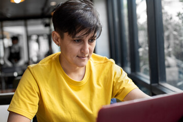 Young woman in trendy yellow colored t-shirt working on computer. Colors of the year 2021.