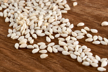 Close up of organic raw white sesame seeds on wooden background