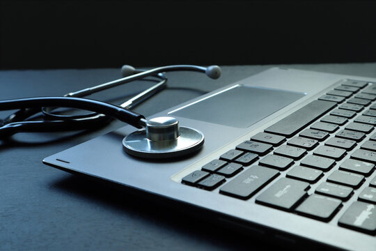 stethoscope , medical mask and laptop are put on the wooden black table of the doctor in the hostpital during relaxing after medical routine work