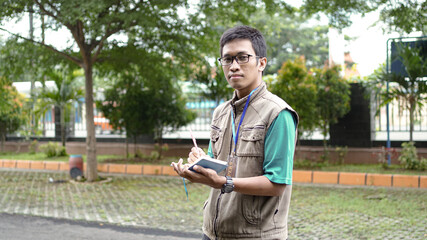 asian male journalist wear vest and ready writting for news