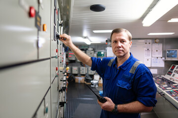 Marine engineer officer controlling vessel engines and propulsion in engine control room ECR. Ship maintenance Start or stop of main engine