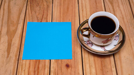 Obraz na płótnie Canvas blank blue paper for quotes with coffee on top wood table