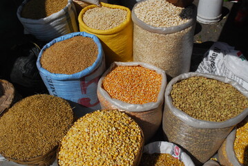Bags of dried grains, beans and seeds for sale at an outdoor farmer's market.