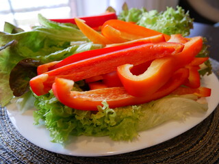 Red bell pepper and green salad leaves. Vegetables on a plate. 