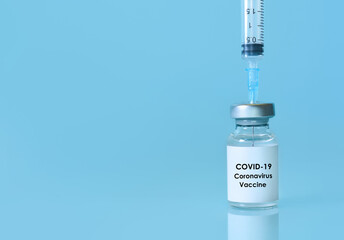 Vaccine in a bottle with a syringe on a blue background.The concept of medicine, healthcare and science.Coronavirus vaccine.Copy space for text.Banner