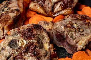 Lamb fried in a pan with carrots close-up.