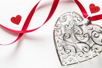 Saint Valentine day greeting card, beautiful silver heart with little red hearts with ribbon on white
