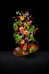 Flying wok ingredients - shrimp, vegetables, pak choi leaves, onions and peanuts. Asian food delivery. Chinese recipes. Wok preparation ingredients. Vertical image.