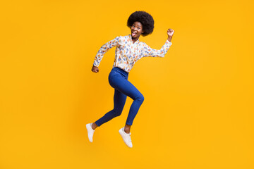 Fototapeta na wymiar Full size profile side photo of brunette girl wear white print shirt blue pants jump run crazy isolated on yellow color background