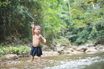 Asian boy playing at the waterfall in Asian countryside