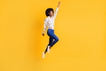 Full body photo of brown haired girl wear blue trousers white print shirt jump up hero isolated on yellow color background