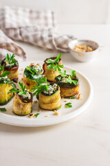 Roasted zucchini rolls stuffed with cheese on white plate