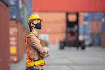 women foreman wear protection face mask stand hand cross with clipboard at loading containers in...