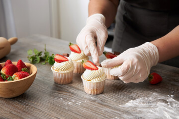 Closeup of a pastry chef decorating cupcakes