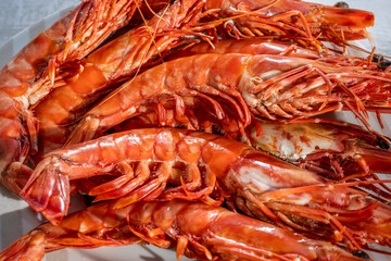 Close-up giant deep-sea shrimps gambas. Boiled prawns on white plate, top view, on wooden background. High quality photo
