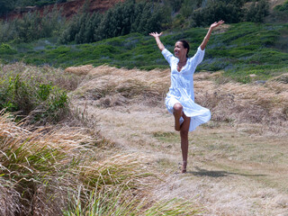 Hawaiin woman raising her arms in joy In a field