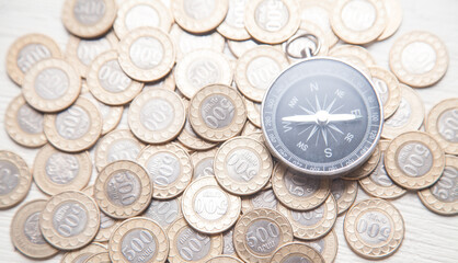 Compass and coins on the white desk.