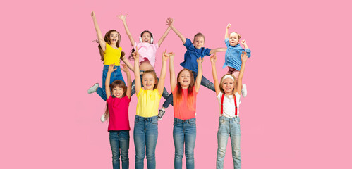 Happiness. Portrait of little caucasian children jumping isolated on pink studio background with copyspace. Cheerful kid models. Concept of human emotions, facial expression, sales, ad, childhood.