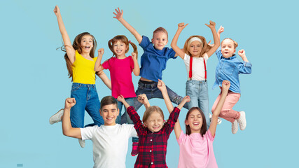 Happy. Portrait of little caucasian children jumping isolated on blue studio background with...
