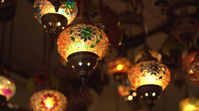 Collection of elegant small traditional Turkish lanterns with mosaic patterns hanging on ceiling of semi-dark room close low angle shot.