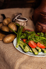 Boiled fresh potatoes in uniform on a wooden board in a cast-iron pan. Russian cuisine. Dinner in the Russian village. salt are on the table. On the background of clay pots