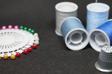 threads , needles, thimbles means for sewing a hobby of needlework on a black background horizontal macro photo