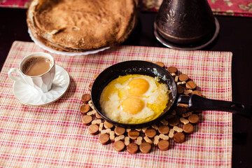 Elegant Restaurant Plate of Fried Eggs Decorated with Fresh Spinach Leaves and Young Pea Shoots on Flat Black Plate. Macro Photo of Healthy Nutritious Breakfast Isolated on White Background