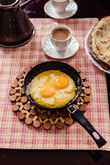 Elegant Restaurant Plate of Fried Eggs Decorated with Fresh Spinach Leaves and Young Pea Shoots on Flat Black Plate. Macro Photo of Healthy Nutritious Breakfast Isolated on White Background