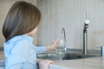 Child open water tap. Kitchen faucet. Glass of clean water. Pouring fresh drink. Hydration. Healthy lifestyle. Water quality check concept. World water monitoring day. Environmental pollution problem - obrazy, fototapety, plakaty
