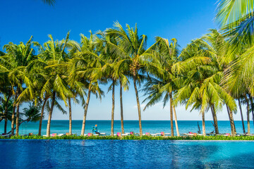 Naklejka premium Chairs and umbrella In palm beach - Tropical holiday banner. White sand and coco palms travel tourism wide panorama background concept and swing under tree