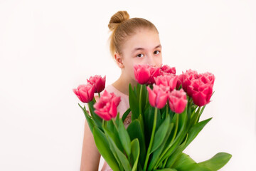 A teenage girl in a pink T-shirt holding a huge bouquet of fresh tulips against a white background