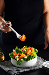 Woman preparing a salad with tomatoes, lettuce, olive oil and salt