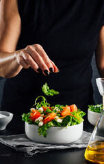 Woman preparing a salad with tomatoes, lettuce, olive oil and salt