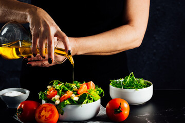 Woman preparing a salad with tomatoes, lettuce, olive oil and salt