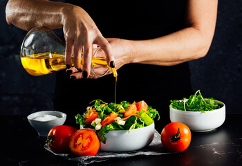 Woman preparing a salad with tomatoes, lettuce, olive oil and salt
