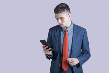 Portrait of a young and stylish boy in a suit who is typing on a smartphone