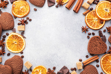 Fototapeta na wymiar Chocolate heart cookies, oranges cinnamon and spicy spices on a gray table, top view, copy space.