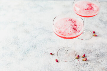 Pink alcoholic cocktail with lemonade, champagne or Martini in a champagne glass, with froth and...
