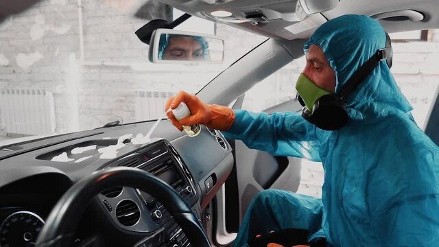 A man applies detergent foam to the dashboard of a car while sitting inside. Slow motion images