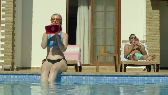 The young woman at the edge of the pool shouts through a small bullhorn.Protest concept.Slow motion video.