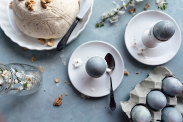 Easter eggs in retro style on a blue table with paschal dish and spring flower. Traditional meal for easter holiday. Vintage and top view.