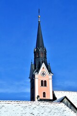 Kirchturm der Pfarrkirche Gleisdorf im Winter vor blauem Himmel