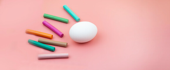 lots of colorful crayons and an egg on a pink background, in the style of a banner
