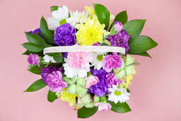 beautiful bouquet of flowers in a light basket on a pink background