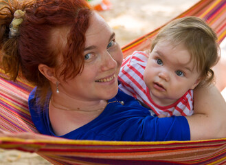 Fototapeta na wymiar Little girl in mom's arms in a hammock